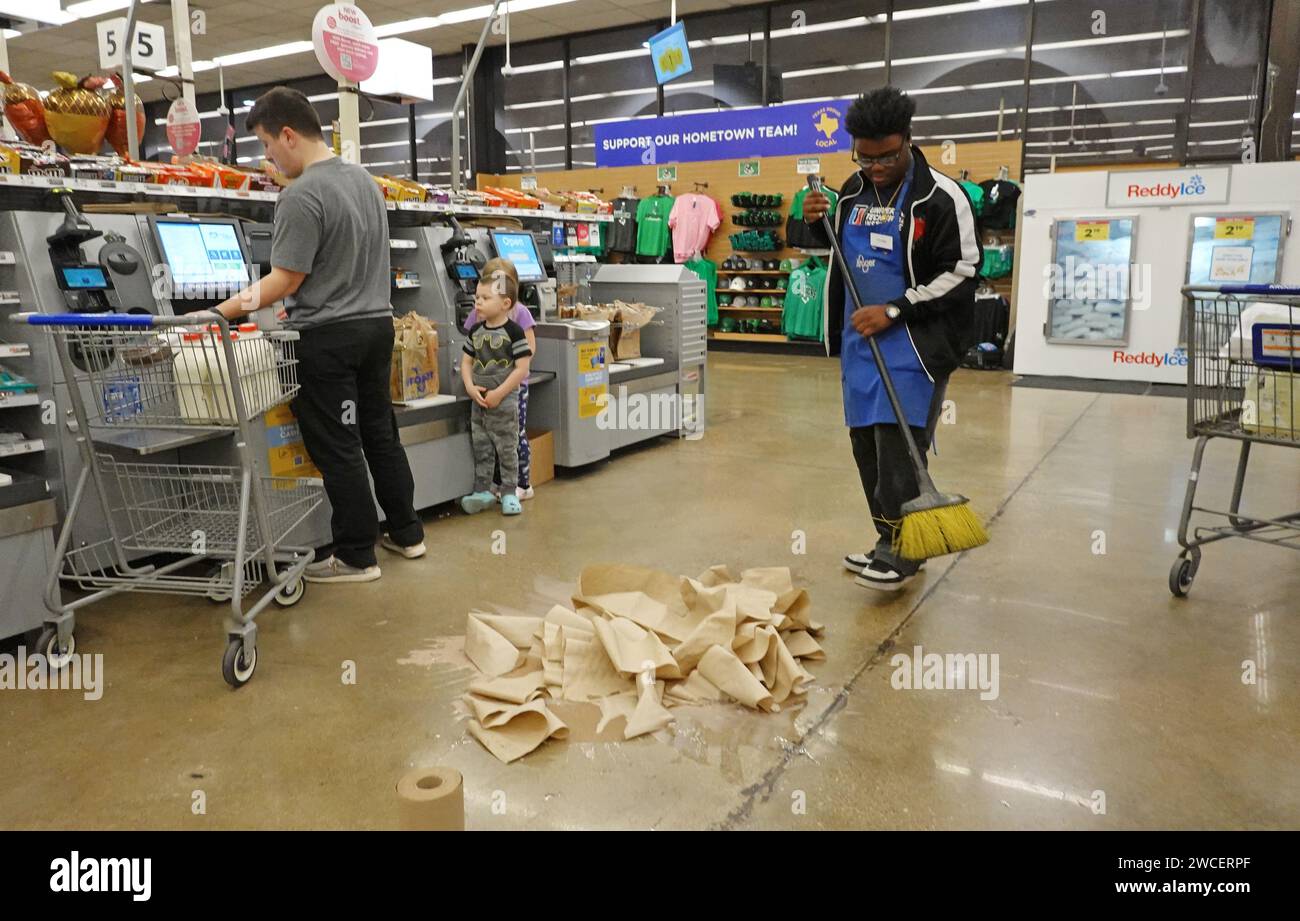 Young African American man cleaning up a broken bottle of milk inside a Kroger grocery store at the self checkout area - November 2023 Stock Photo