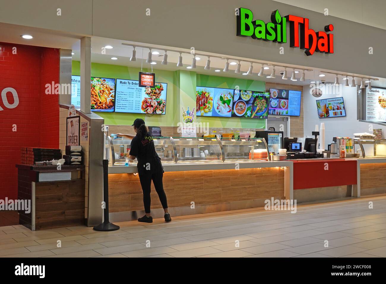 Worker cleaning windows at a Basil Thai restaurant in a food court