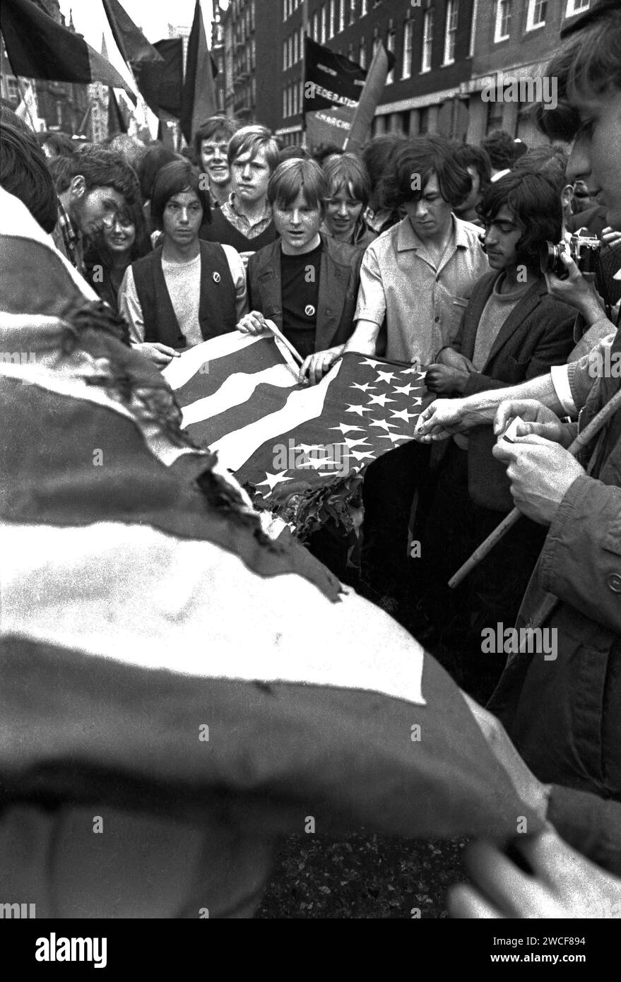 Demonstrators on Grosvenor Street in London attempting to burn an American flag near the US Embassy in Grosvenor Square at the anti-Vietnam protest march on 17th March, 1968 . Due to the violent clash between demonstrators and police this massive protest became known as 'The battle of Grosvenor Square' and was the inspiration for the Rolling Stones song, 'Street Fighting Man'. Stock Photo