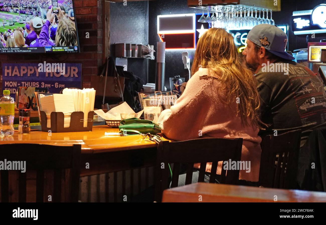 Patrons sit at a bar and watch sports at a Texas Roadhouse restaurant