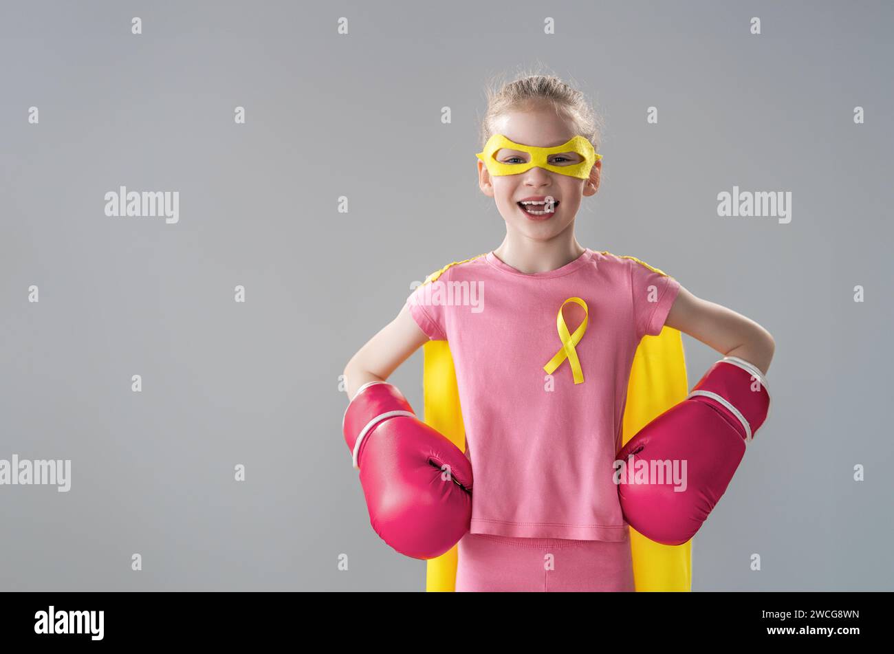 Child in boxing gloves with a yellow ribbon as a symbol of the fight against cancer. Increasing the level of knowledge about kids who have overcome tu Stock Photo