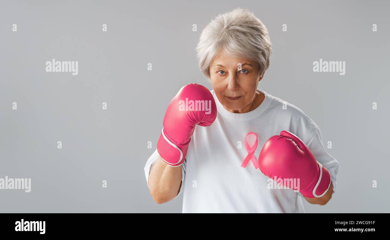 Woman in boxing gloves with a pink ribbon as a symbol of the fight against cancer. Increasing the level of knowledge about people who have overcome tu Stock Photo