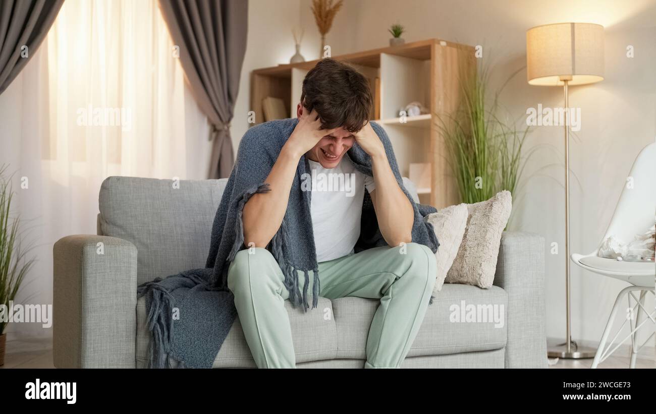 Headache suffer sickness man plaid couch home Stock Photo Alamy