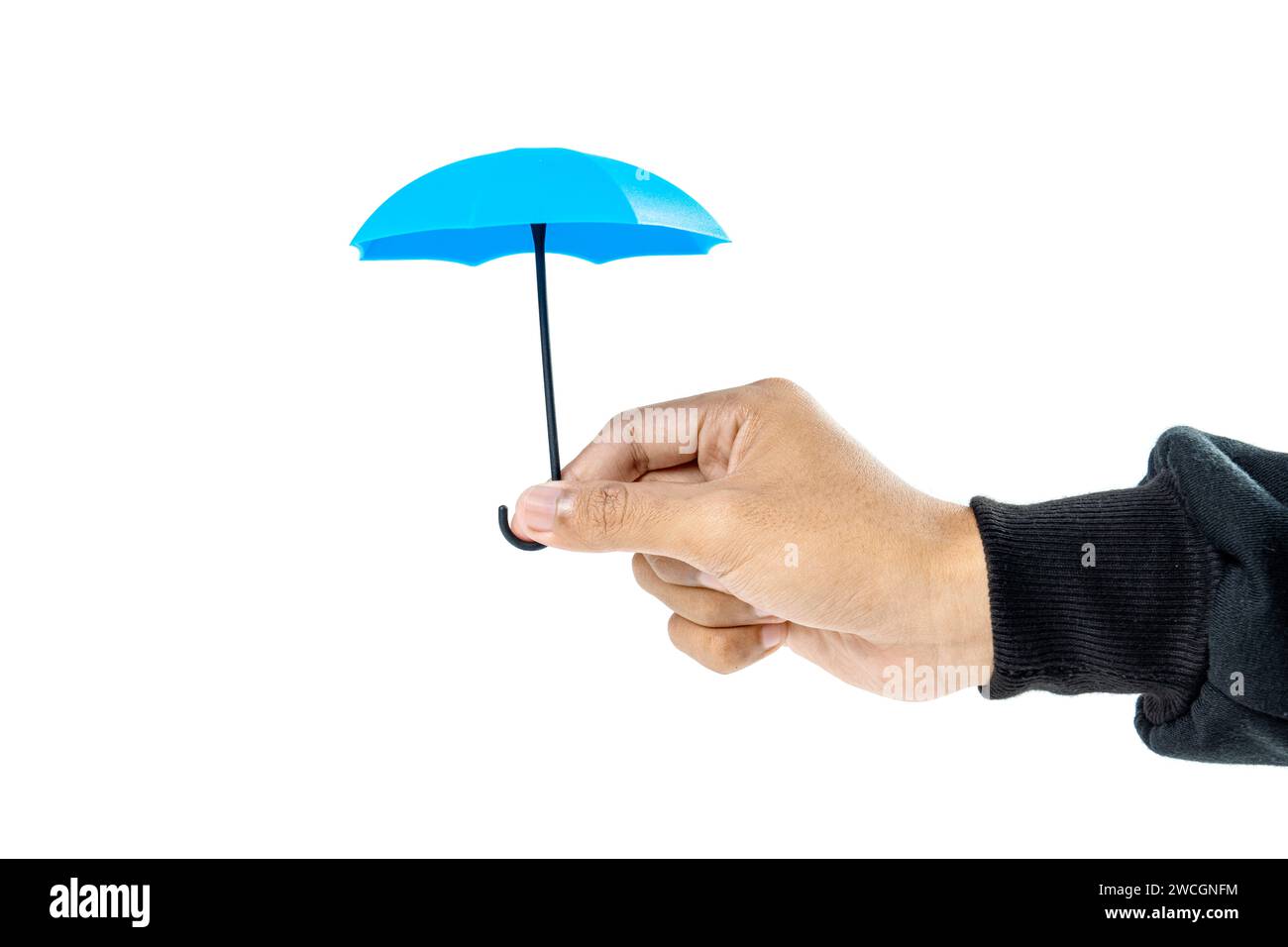 A human hand holding a small blue umbrella is isolated over a white