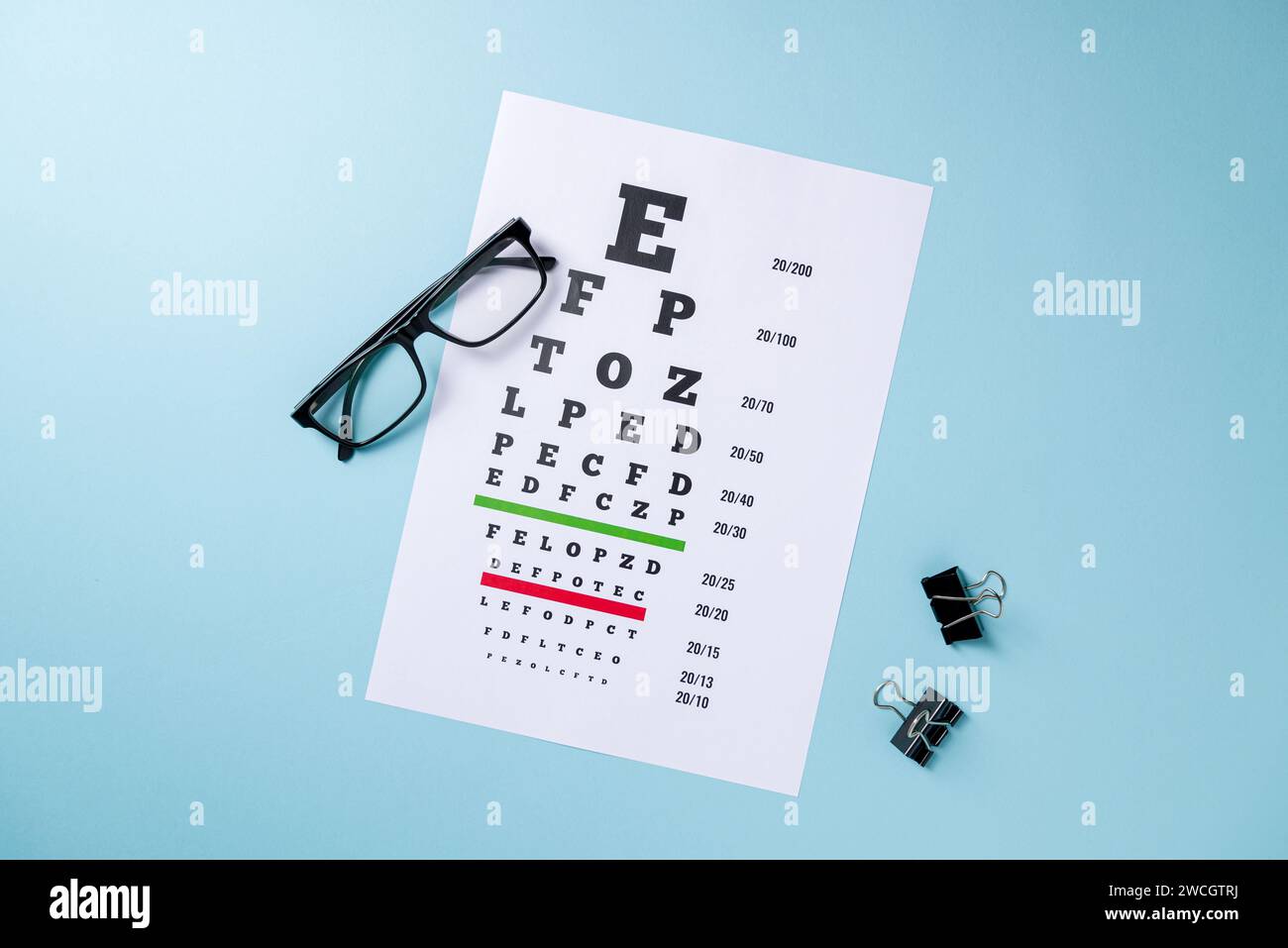 Eye test chart and glasses on blue background Stock Photo
