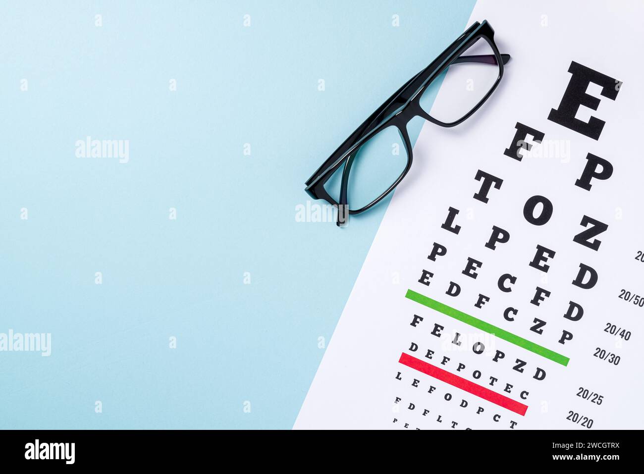 Eye test chart and glasses on blue background Stock Photo
