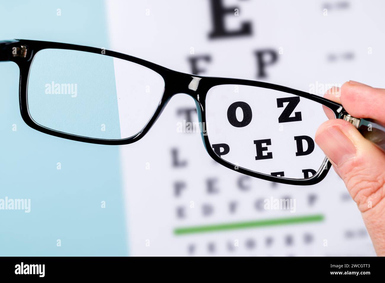 The eye test chart is seen through the glasses. Areas outside the glasses are blurred Stock Photo