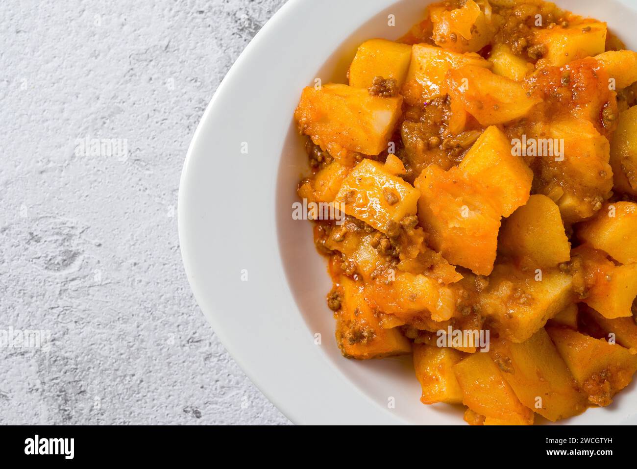 Minced meat and potato dish on white porcelain plate on stone table Stock Photo