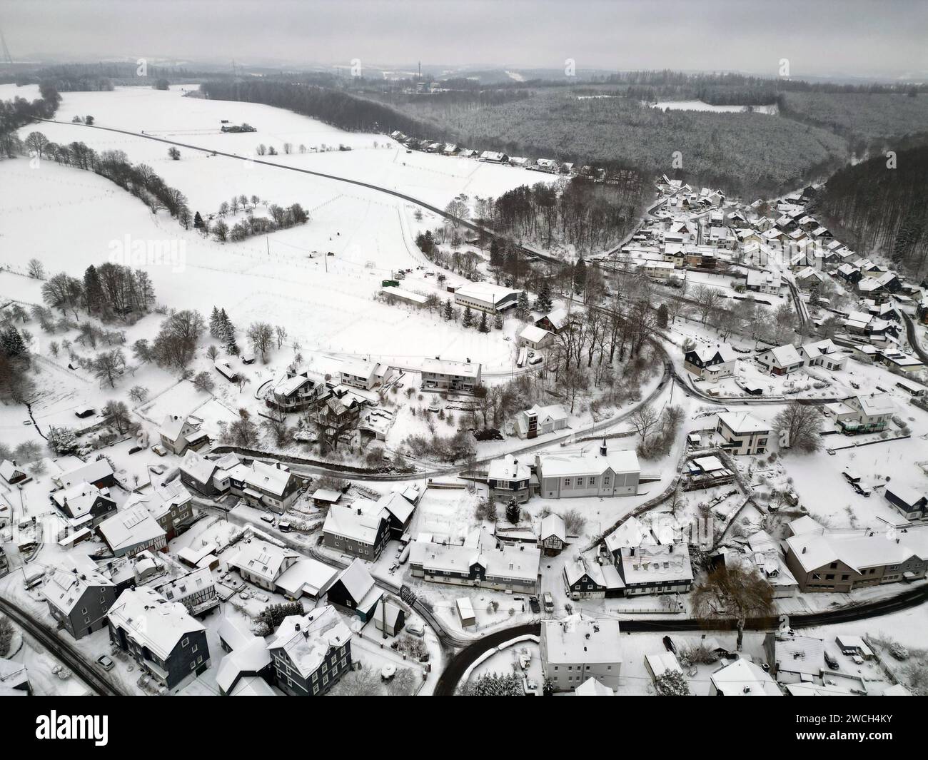 Luftaufnahme. Winter im Siegerland. Blick ueber über die verschneite Landschaft und den Ort Siegen-Oberschelden. Der Himmel ist grau. Winter im Siegerland am 16.01.2024 in Siegen/Deutschland. *** Aerial view winter in Siegerland View over the snowy landscape and the village Siegen Oberschelden The sky is gray Winter in Siegerland on 16 01 2024 in Siegen Germany Stock Photo