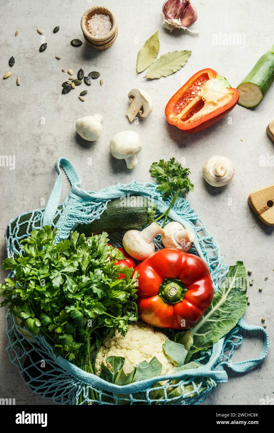 Various healthy organic vegetables in blue mesh grocery bag on kitchen table , top view. Healthy food cooking ingredients Stock Photo