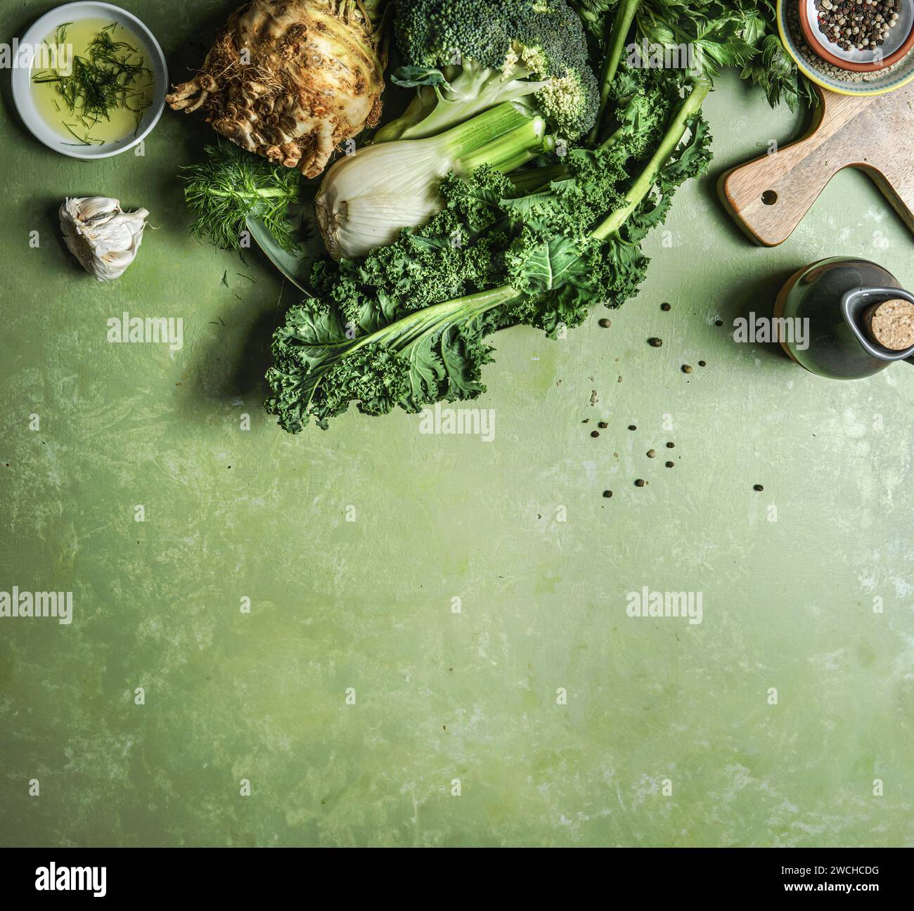 Green vegetables: broccoli, celery, fennel and kale on kitchen table with cooking ingredients, top view with copy space. Border Stock Photo