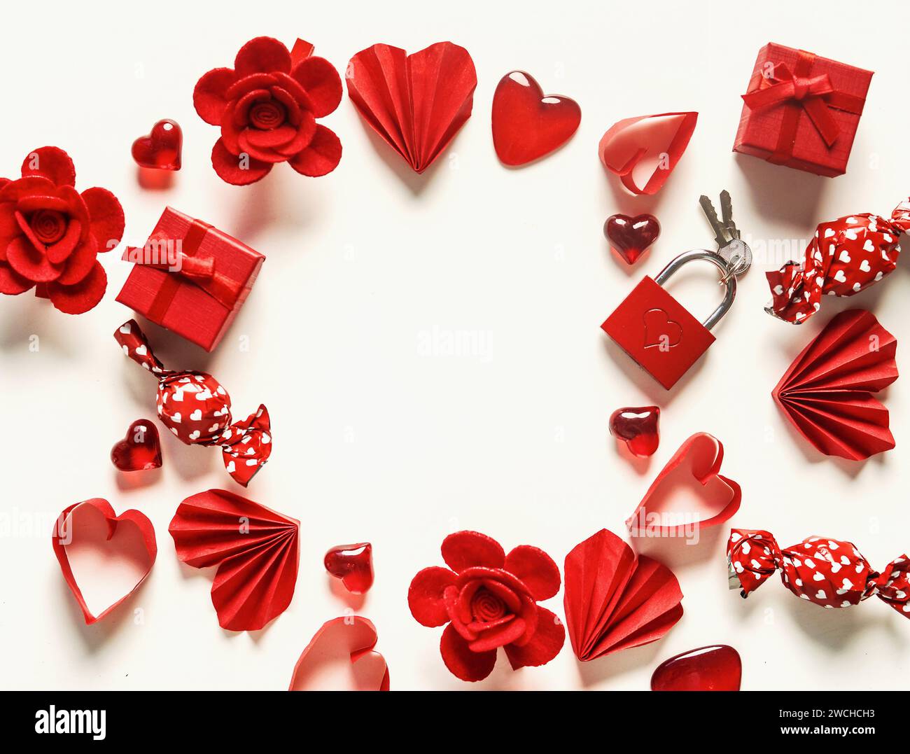 Valentine's day frame made with red hearts, flowers and candies on white background, top view Stock Photo