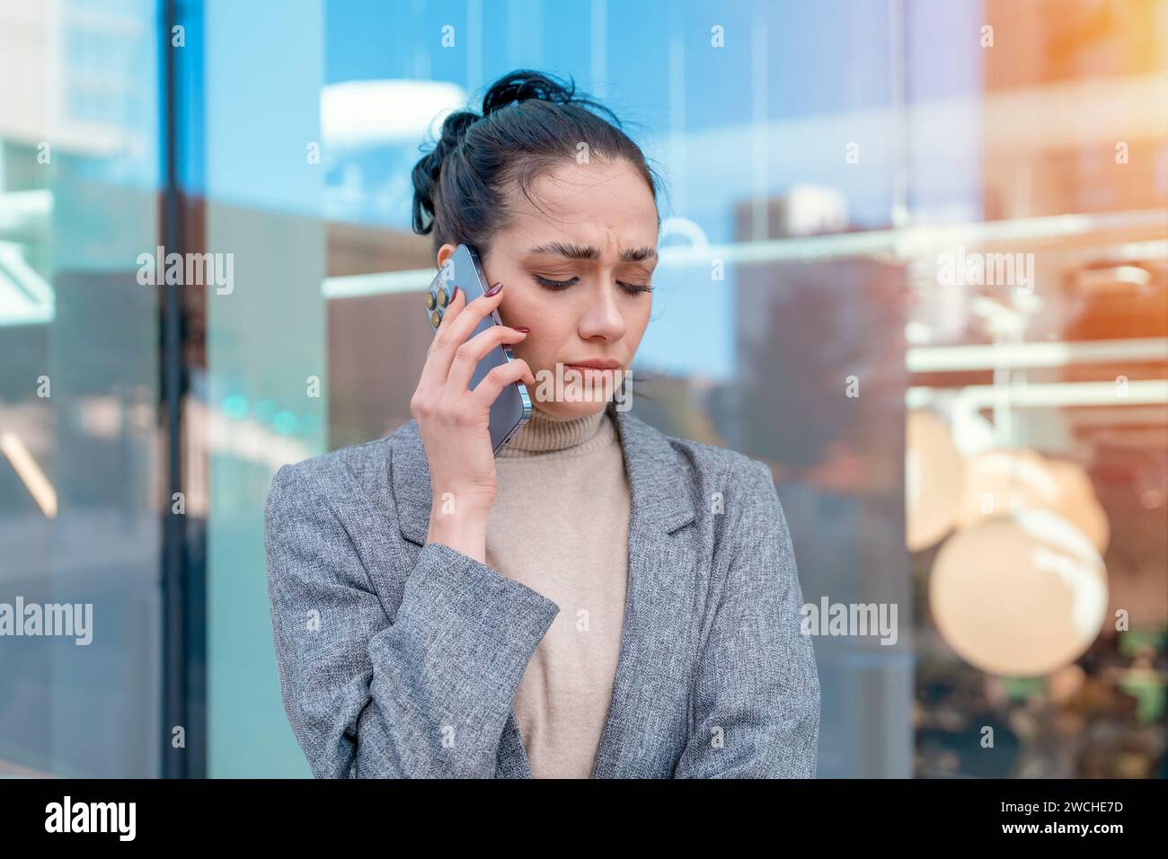 unhappy woman or student  in a jacket and jeans crossing the road and talking on the phone Stock Photo