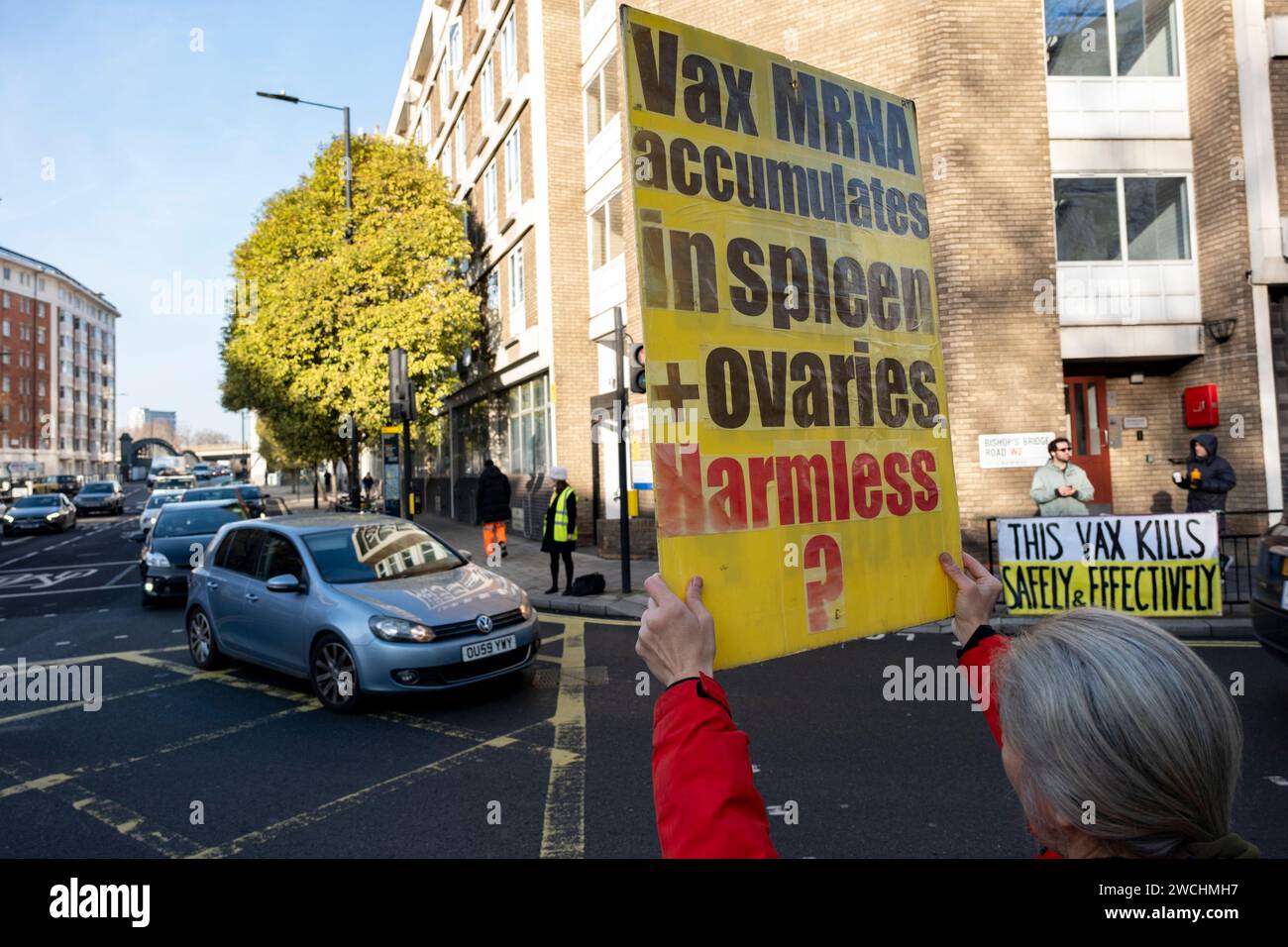 Anti-vax protesters holding yellow placards with anti vaccine slogans on the first day that former Prime Minister Boris Johnson attended the UK Covid-19 Enquiry on 6th December 2023 in London, United Kingdom. The UK Covid-19 Inquiry is an independent public inquiry into the UK’s response to, and the impact of the coronavirus pandemic. Vaccine hesitancy groups known as anti-vaxxers or anti vax, are generally against vaccination. Stock Photo