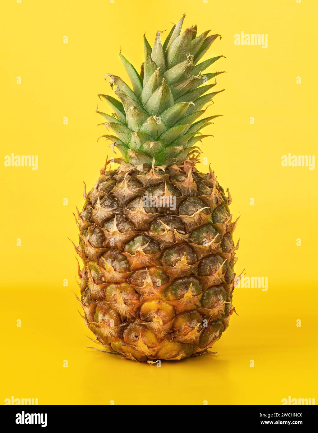 Whole pineapple on yellow background. Stock Photo