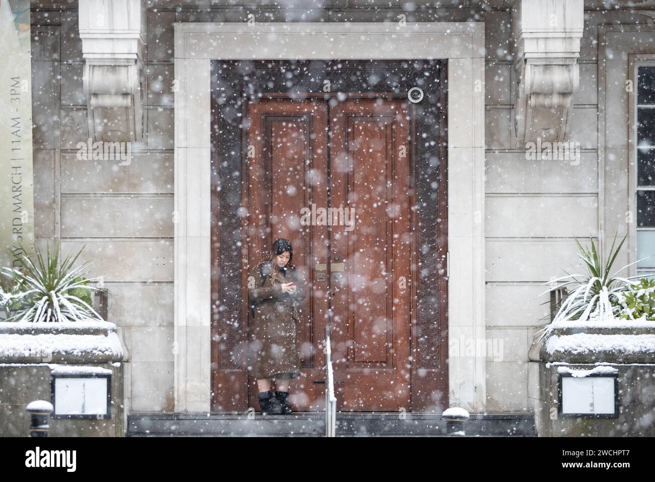 Manchester, UK. 16th Jan, 2024. A woman shelters after during snowfall