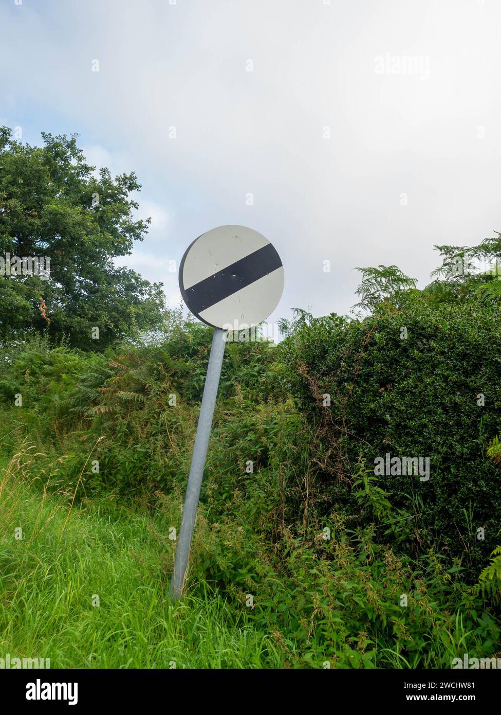 National speed limit leaning towards the hedgerow. Stock Photo