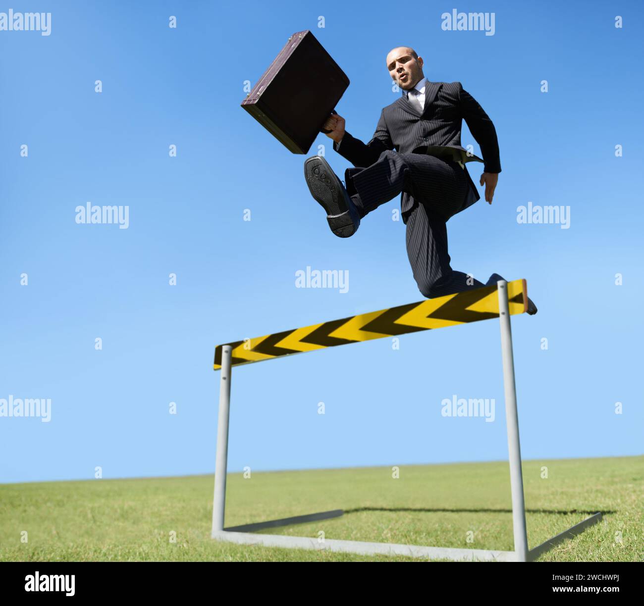 Businessman, hurdle and jumping for career challenge or competition or employee obstacles, growth or achievement. Male person, briefcase and leap at Stock Photo