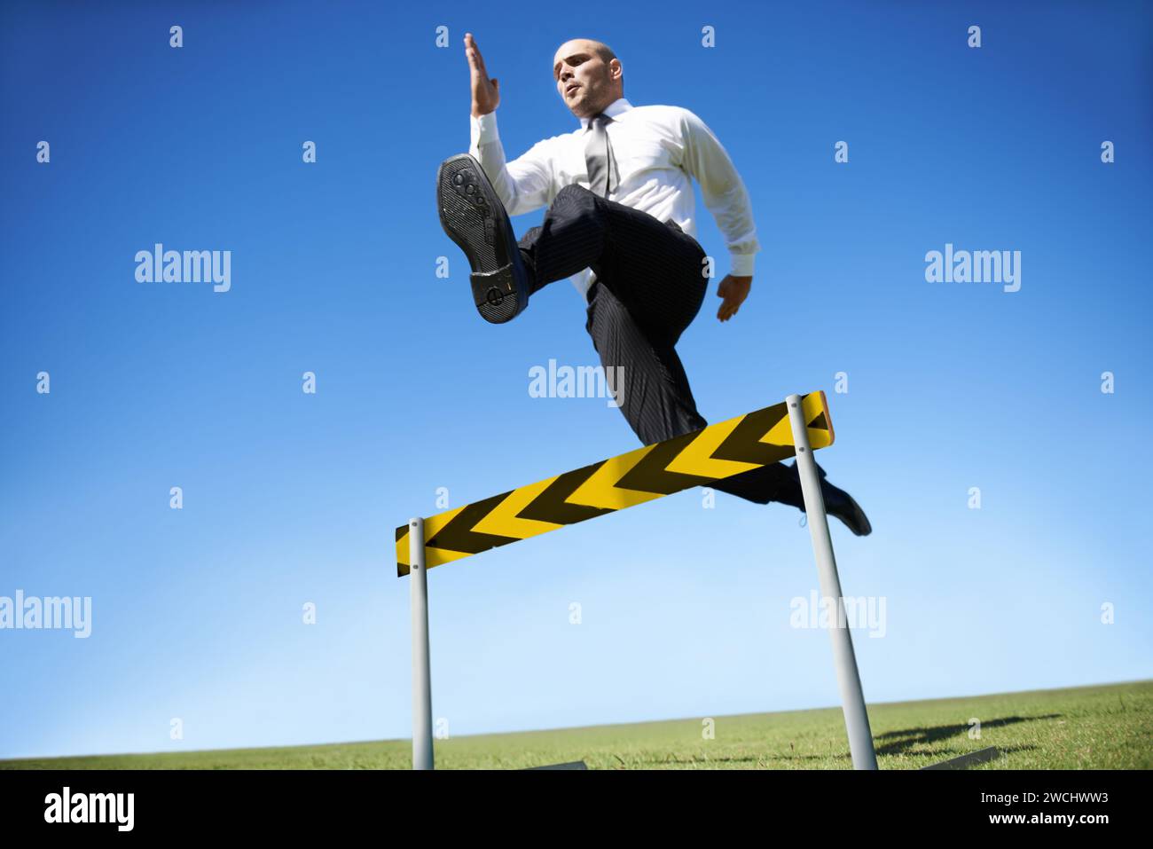 Businessman, hurdle and jumping for career obstacle or competition or employee challenge, growth or achievement. Male person, leap and work Stock Photo