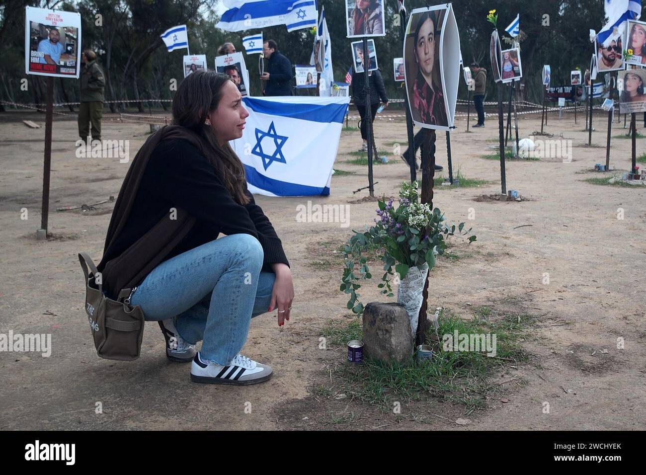 A young Israeli woman cries as she sits next next to a photo of her friend Ayelet Arnin, 22, killed by Hamas militants during the October 7 attacks at the site where the Supernova music festival took place near Kibbutz Reim amid continuing battles between Israel and the militant group Hamas on January 14, 2024 in Gaza border, Israel. Stock Photo