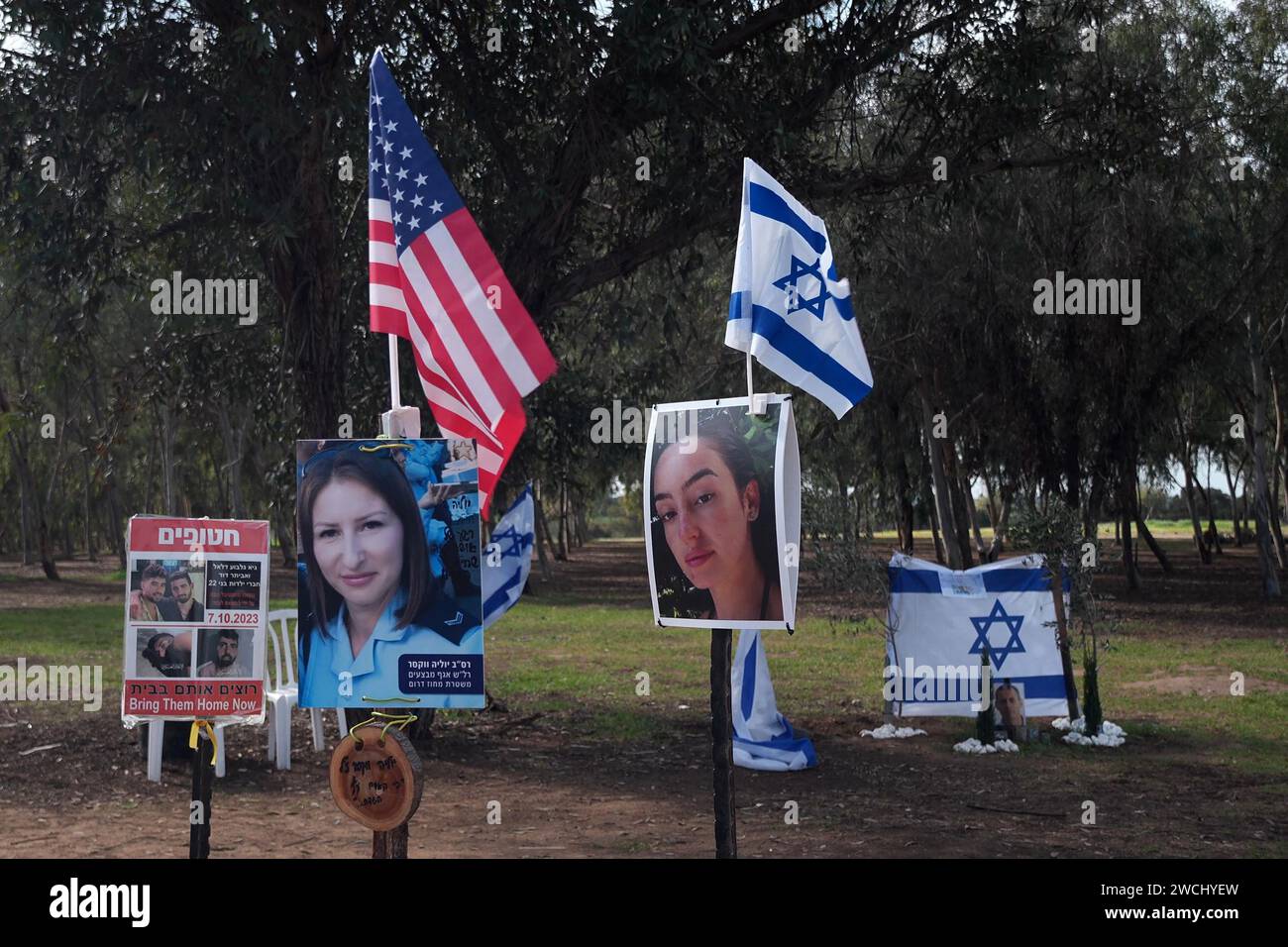 The flag of the U.S. and Israeli flags stand at an installation bearing portraits of Israeli people taken captive or killed by Hamas militants during the October 7 attacks at the site where the Supernova music festival took place near Kibbutz Reim amid continuing battles between Israel and the militant group Hamas on January 14, 2024 in Gaza border, Israel Stock Photo