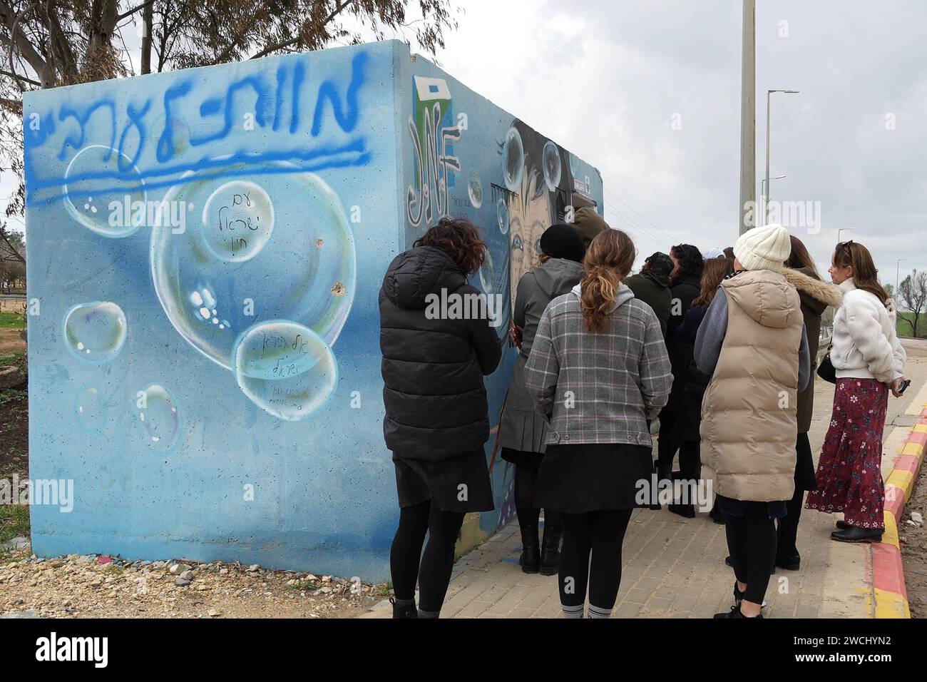 People visit a bomb shelter that is sprayed with a text that reads 'Death to Arabs' where Israeli Supernova festival goers were hiding and killed by Hamas militants on October 7th near Kibbutz Bee'ri on January 14, 2024 in Gaza border, Israel Stock Photo