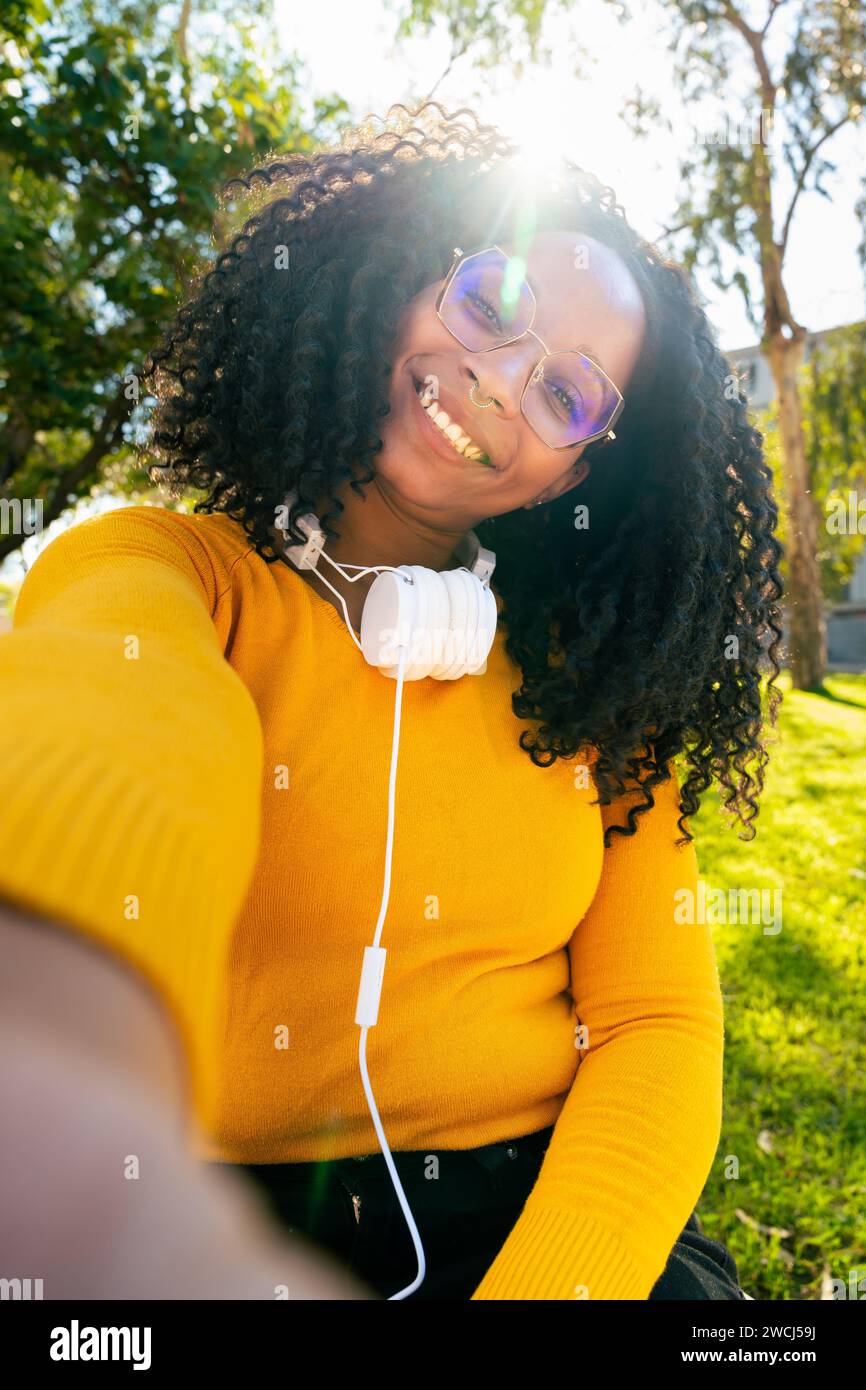 Beautiful woman with glasses curly hair smiling making a self portrait. Stock Photo