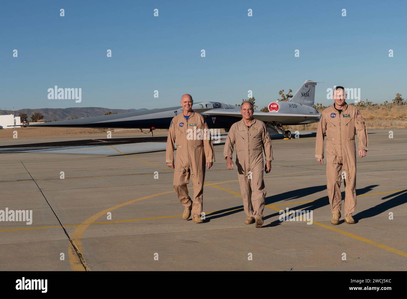 Test pilots Nils Larson (left) and Jim 'Clue' Less (right) and Lockheed Martin test pilot Dan 'Dog' Canin pose with NASA's X-59 quiet supersonic research aircraft, pictured on December 12, 2023, as it sits on the apron outside Lockheed Martin's Skunk Works facility in Palmdale, California. NASA and Lockheed Martin formally debuted the one-of-a-kind experimental airplane on Friday, January 12, 2024. The X-59 is the centerpiece of NASA's Quesst mission, which seeks to address one of the primary challenges to supersonic flight over land by making sonic booms quieter. NASA Photo by Steve Freeman/U Stock Photo