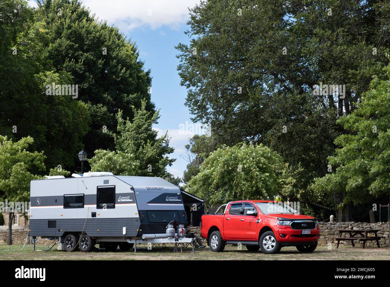 Landscape view of a a large caravan and a red modern 4WD vehicle at camp in Ross, Tasmania Stock Photo