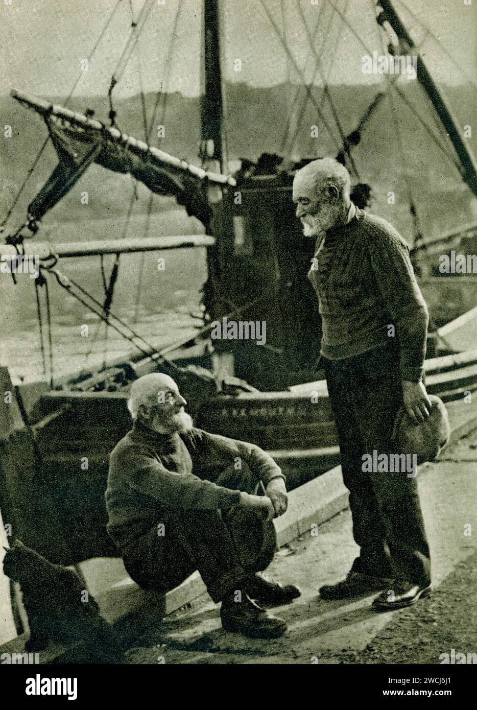 Early 1900's 1930's era photograph of two fishermen of Eyemouth, chatting on the quayside, from the book 'In Scotland Again' by H. V. Morton. (first pub 26 Oct. 1933) Eyemouth, Berwickshire, Scotland,  U.K. Stock Photo