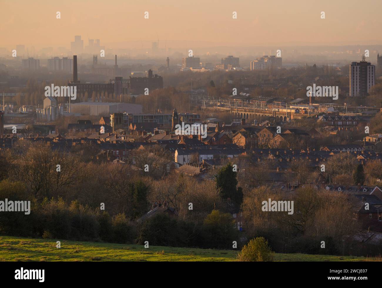 General view of factories and residential housing with the Manchester skyline in the distance Stock Photo