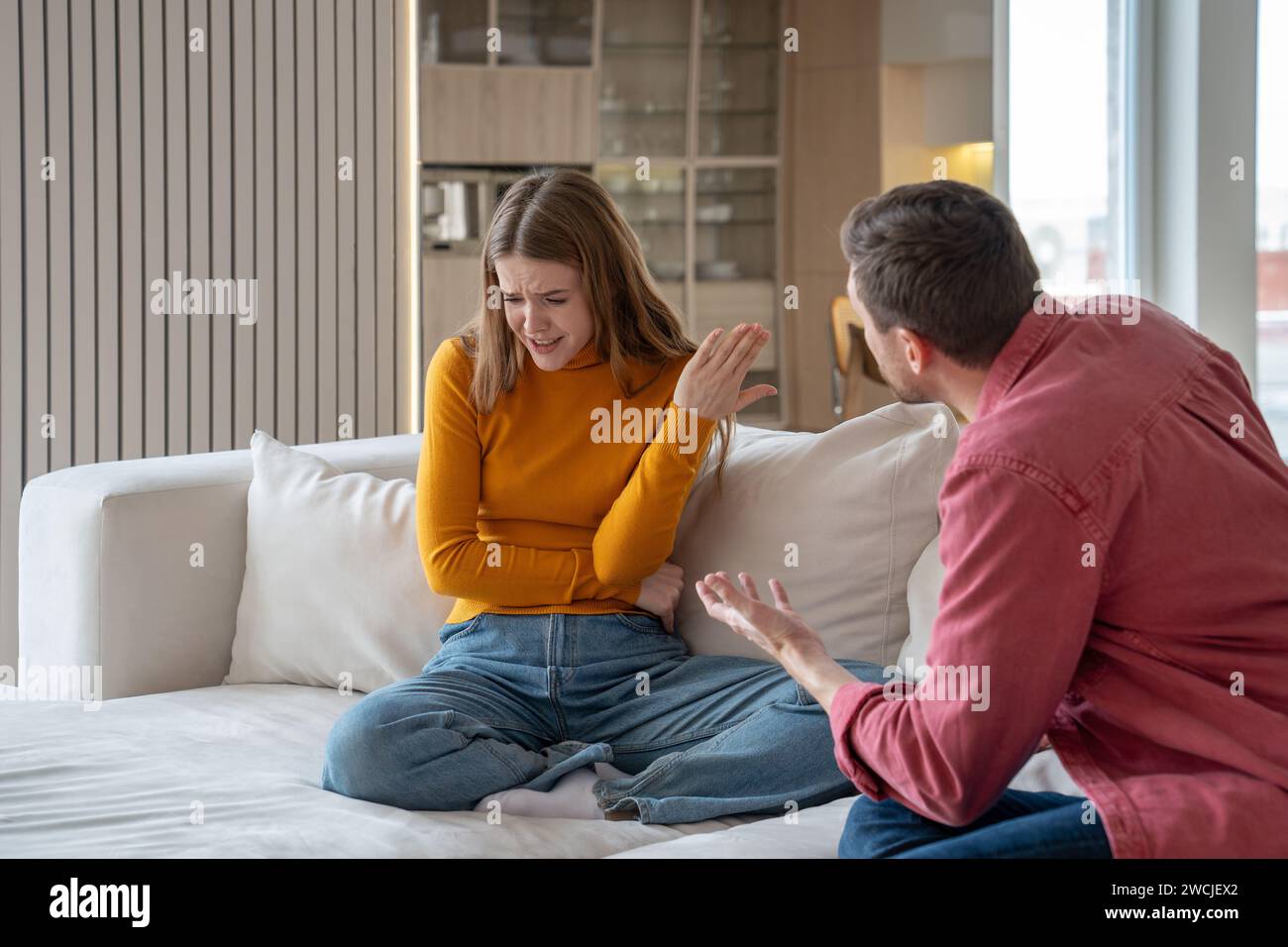 Family couple having scandal, misunderstanding sitting on couch at home. Sad woman talk with husband Stock Photo