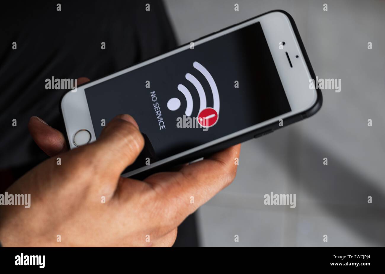 Close up of male hand holding a smart phone with sign no service on screen. Communication, cellular problem, bad connection concept. Stock Photo