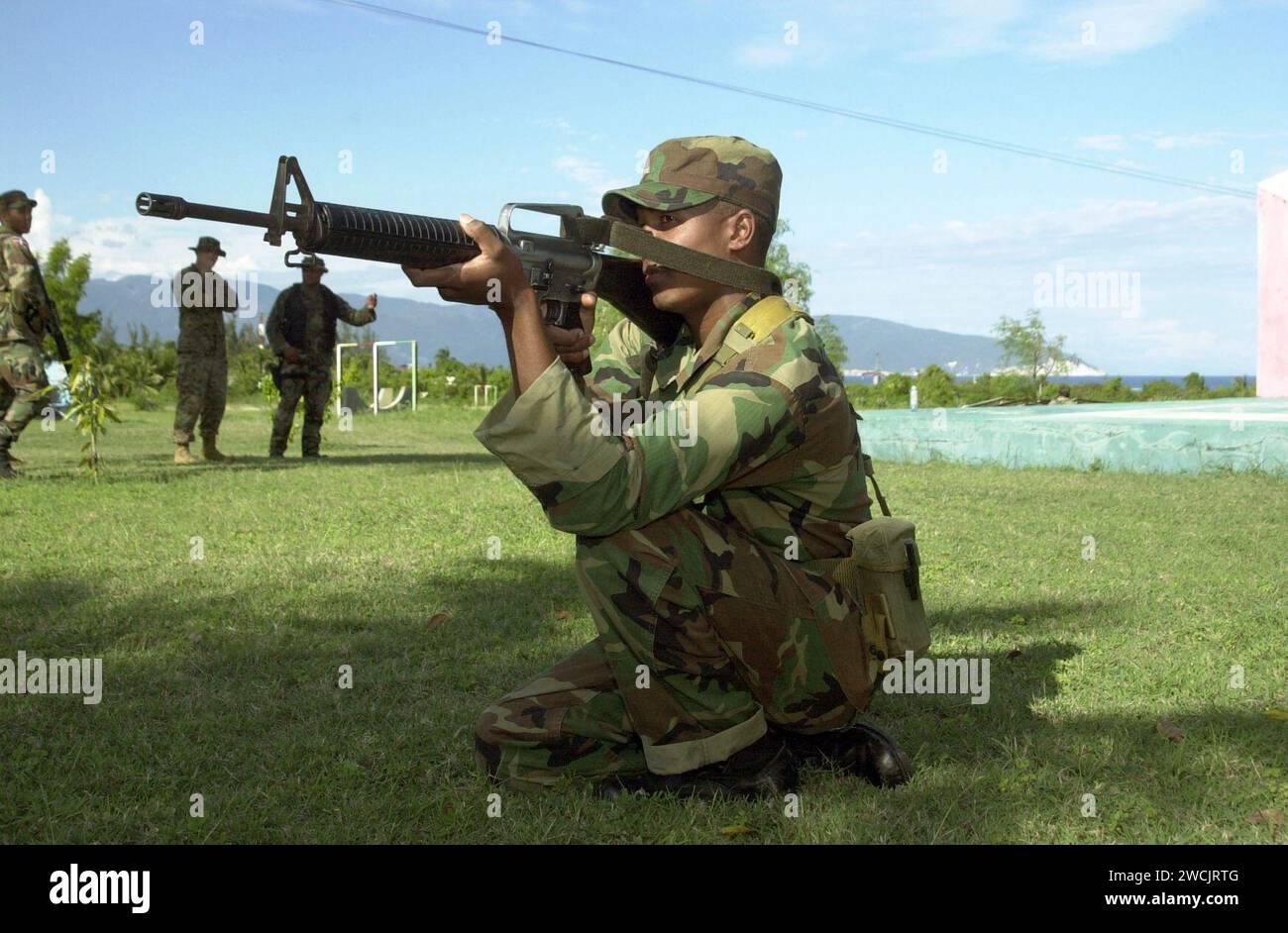 A Dominican Republic Armed Forces Soldier, asigned to Delta Company, 1ST Caribbean Battalion, aims his 5.56 mm M-16 assault rifle in the kneeling prone position on April 18, 2004, at Barahona Army Base, Dominican Republic DA-SD-07-32444. Stock Photo