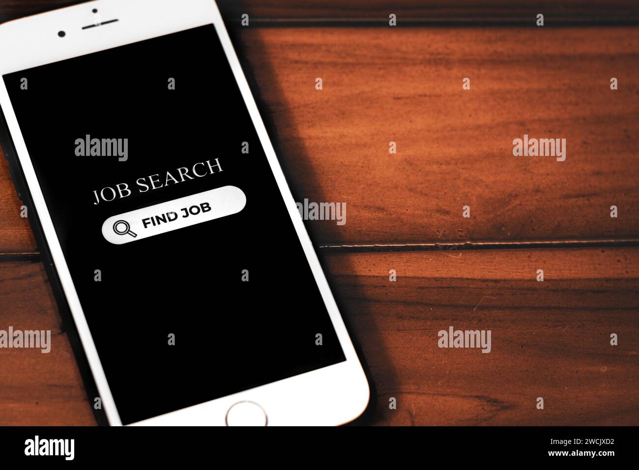 Job Search Concept. Smartphone with job search app on screen on wooden background. Browsing job opportunities online. Stock Photo