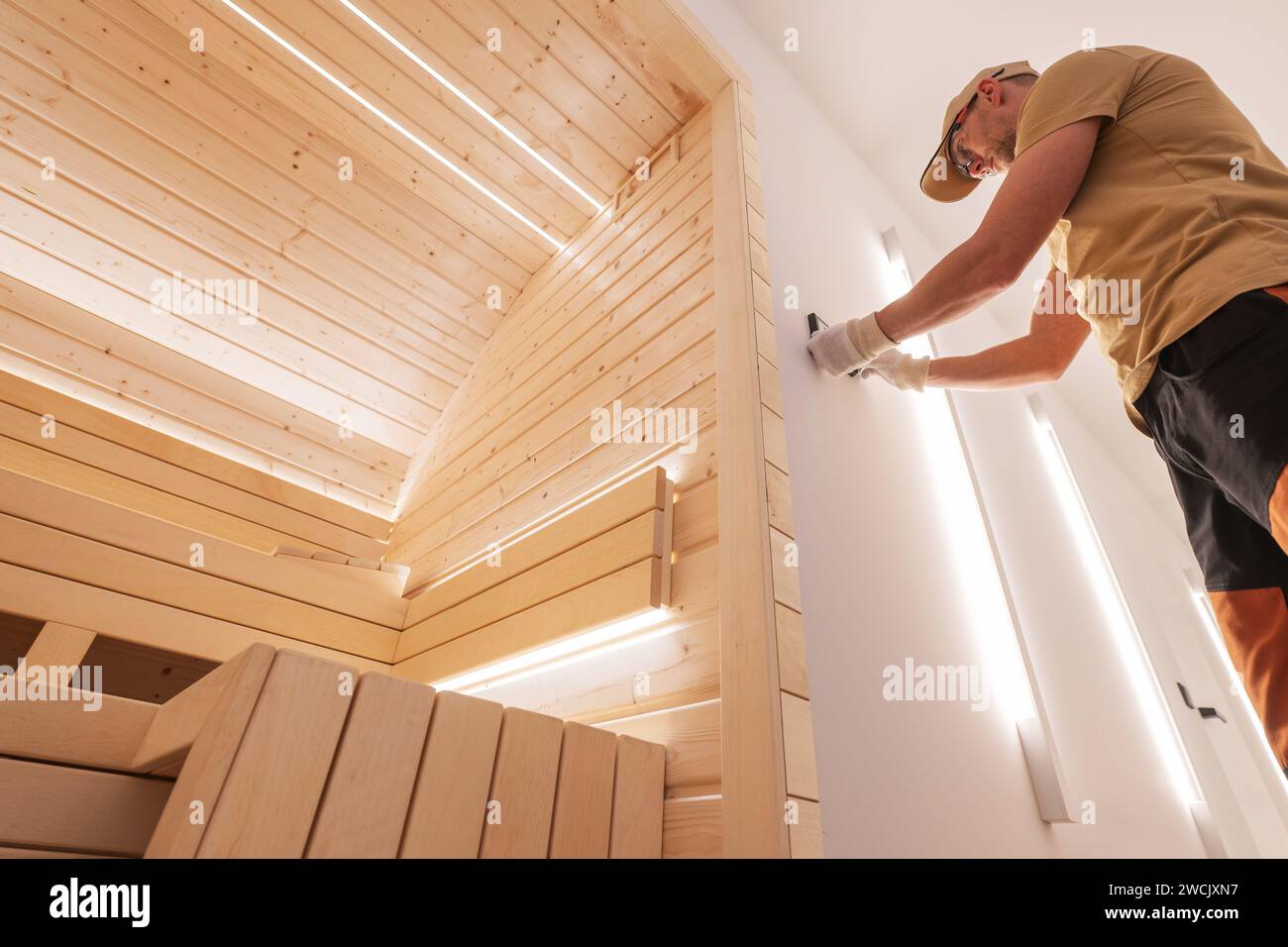 Caucasian SPA and Wellness Specialist Installing Thermostat to Residential Finnish Sauna Stock Photo