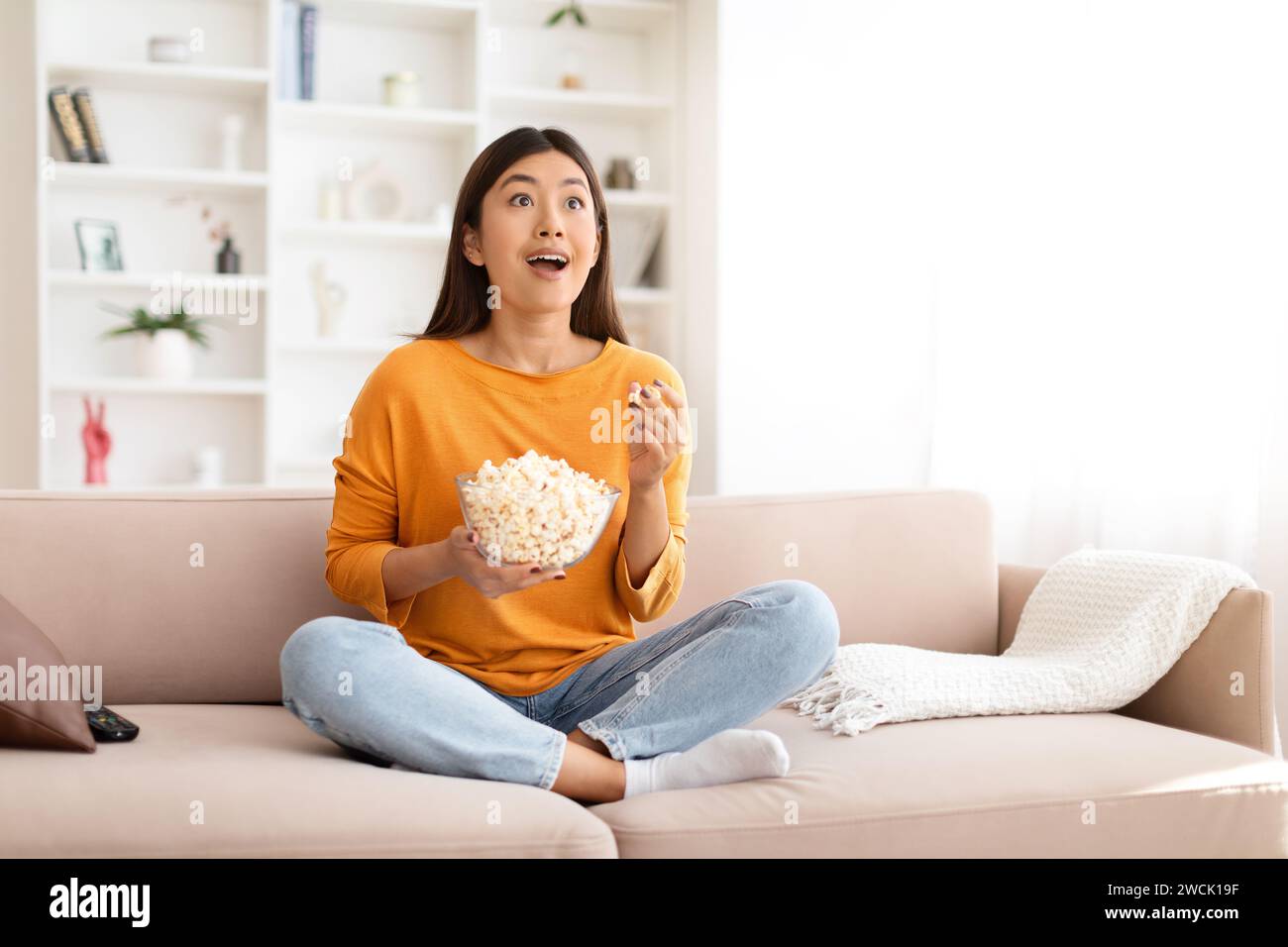 Amazed young asian woman watching movie or Tv program Stock Photo