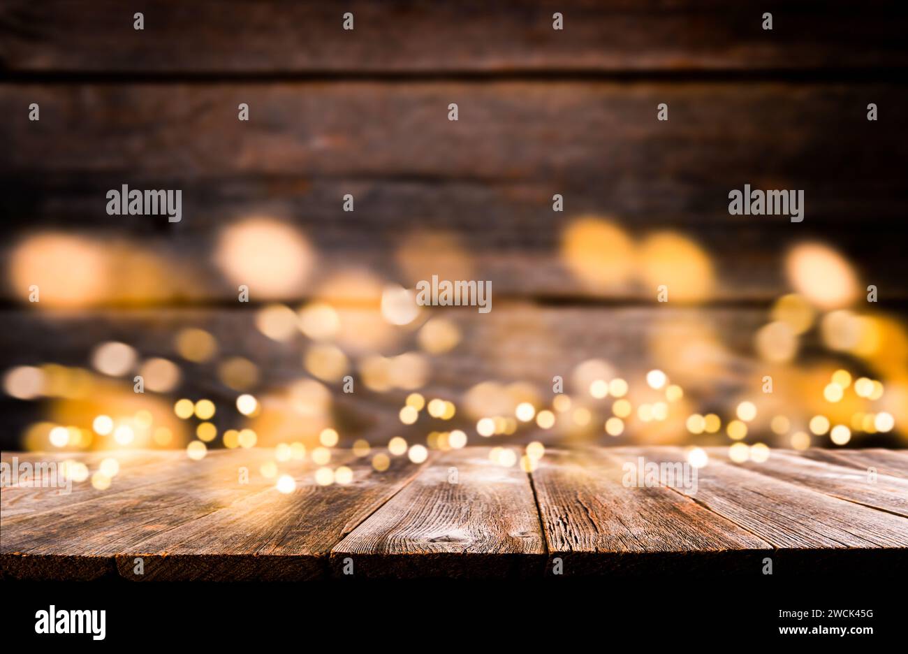 Empty rustic wooden table with blurred glitter lights background. Christmas lights on empty wooden table. Xmas holidays wallpaper. Stock Photo