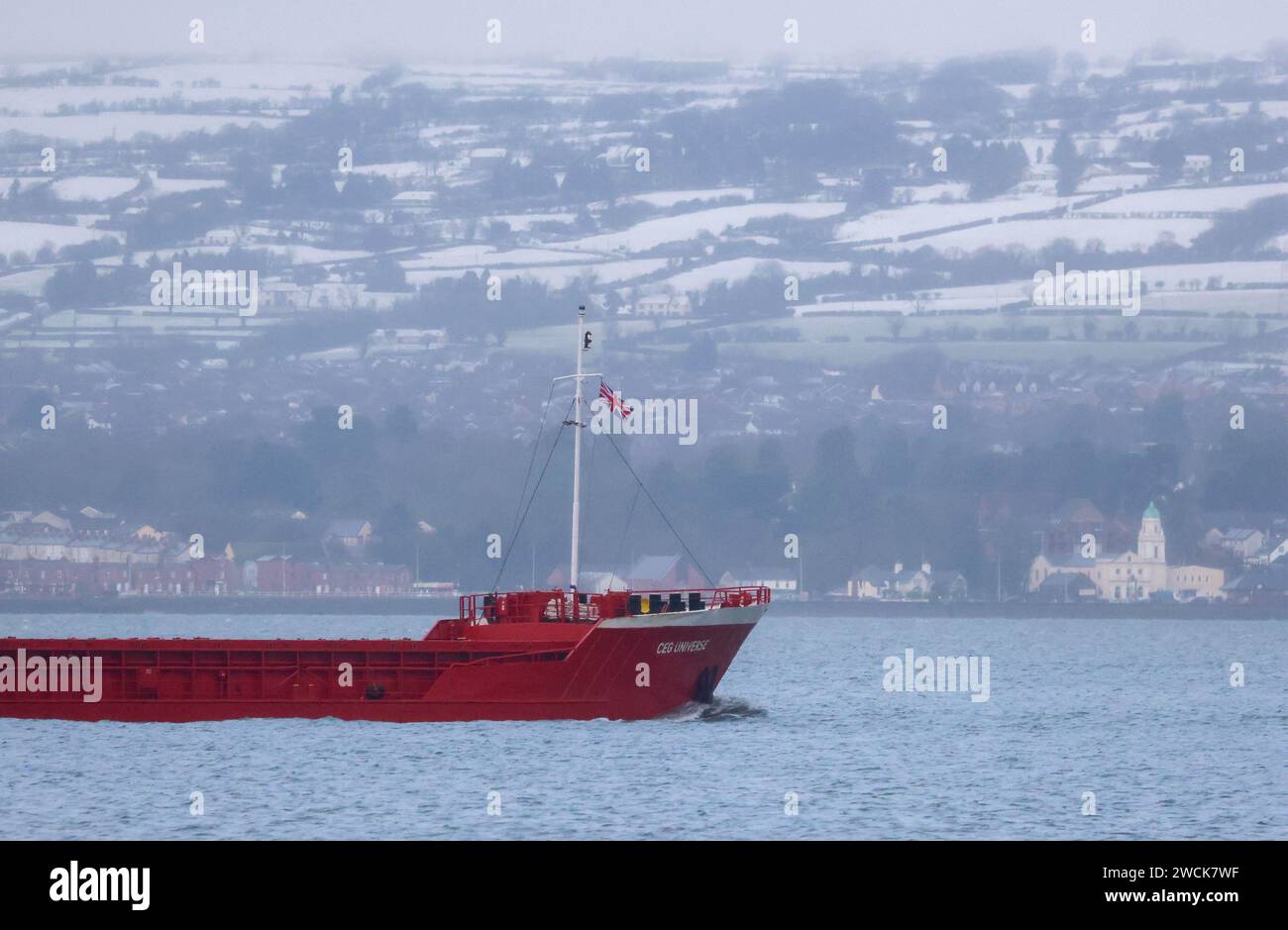 Holywood, County Down, Northern Ireland, UK. 16th Jan 2024. UK weather - a cold start with snow over the Antrim hills on the opposite side of Belfast Lough. General cargo ship CEG Universe sails down Belfast Lough on a winter day in January as the cold snap continues. Credit: CAZIMB/Alamy Live News. Stock Photo