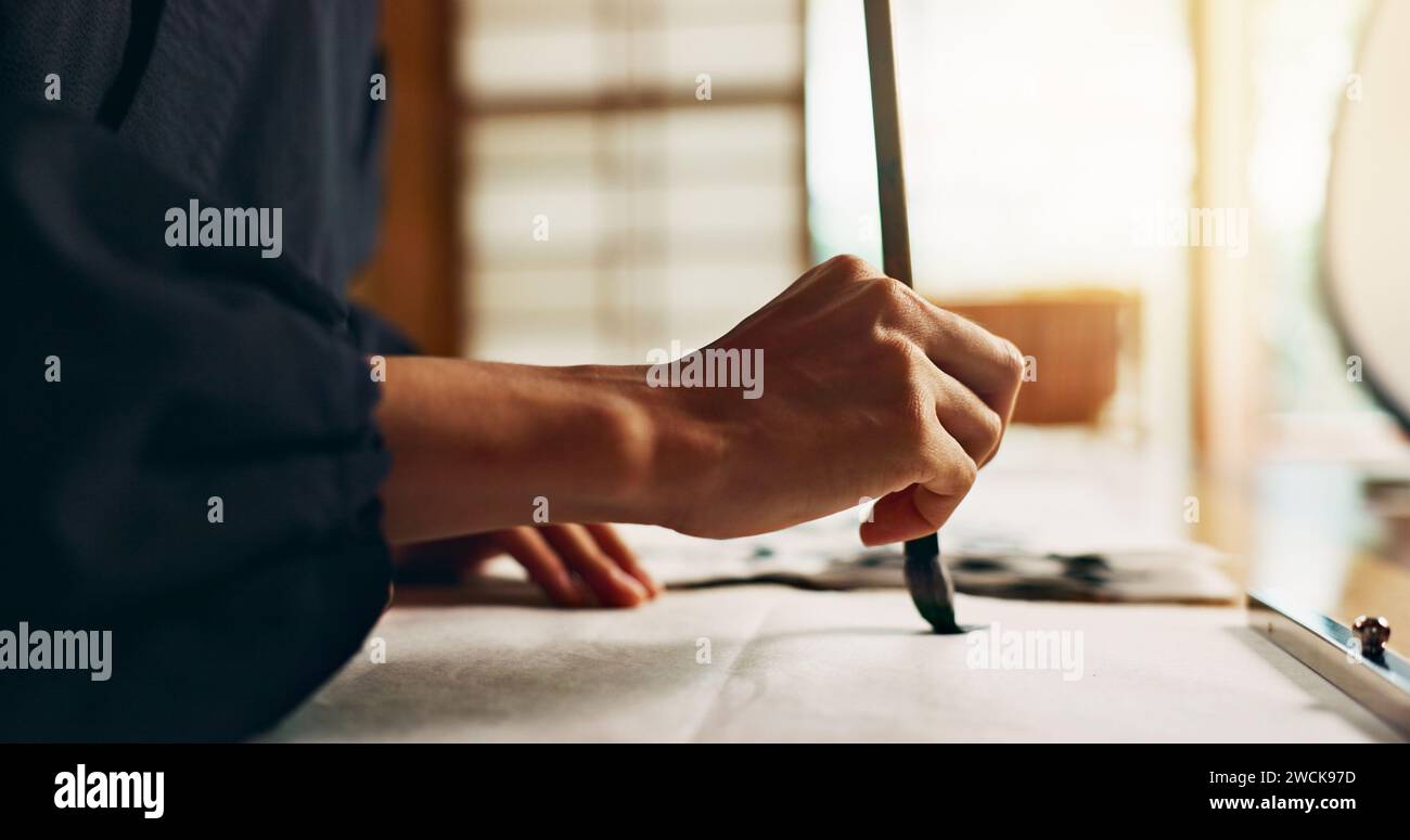 Hands, brush for writing and ancient script for art, calligraphy and closeup with alphabet. Japanese, creativity and vintage tools, paintbrush and Stock Photo