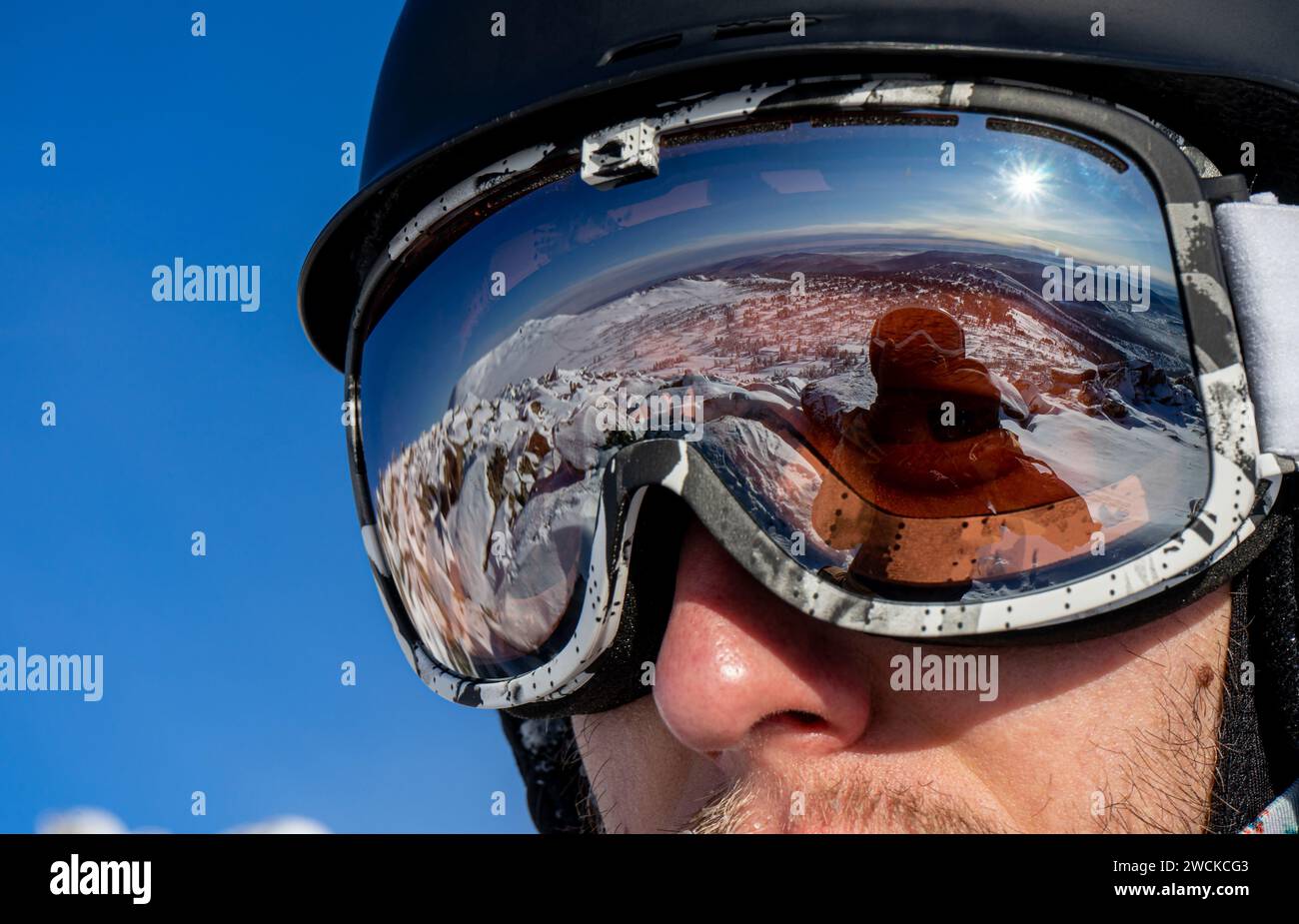 Reflection in ski goggles close-up: snowy mountain slopes for skiing. Skier's or snowboarder equipment: helmet, mask, glasses on man. Weekend active s Stock Photo