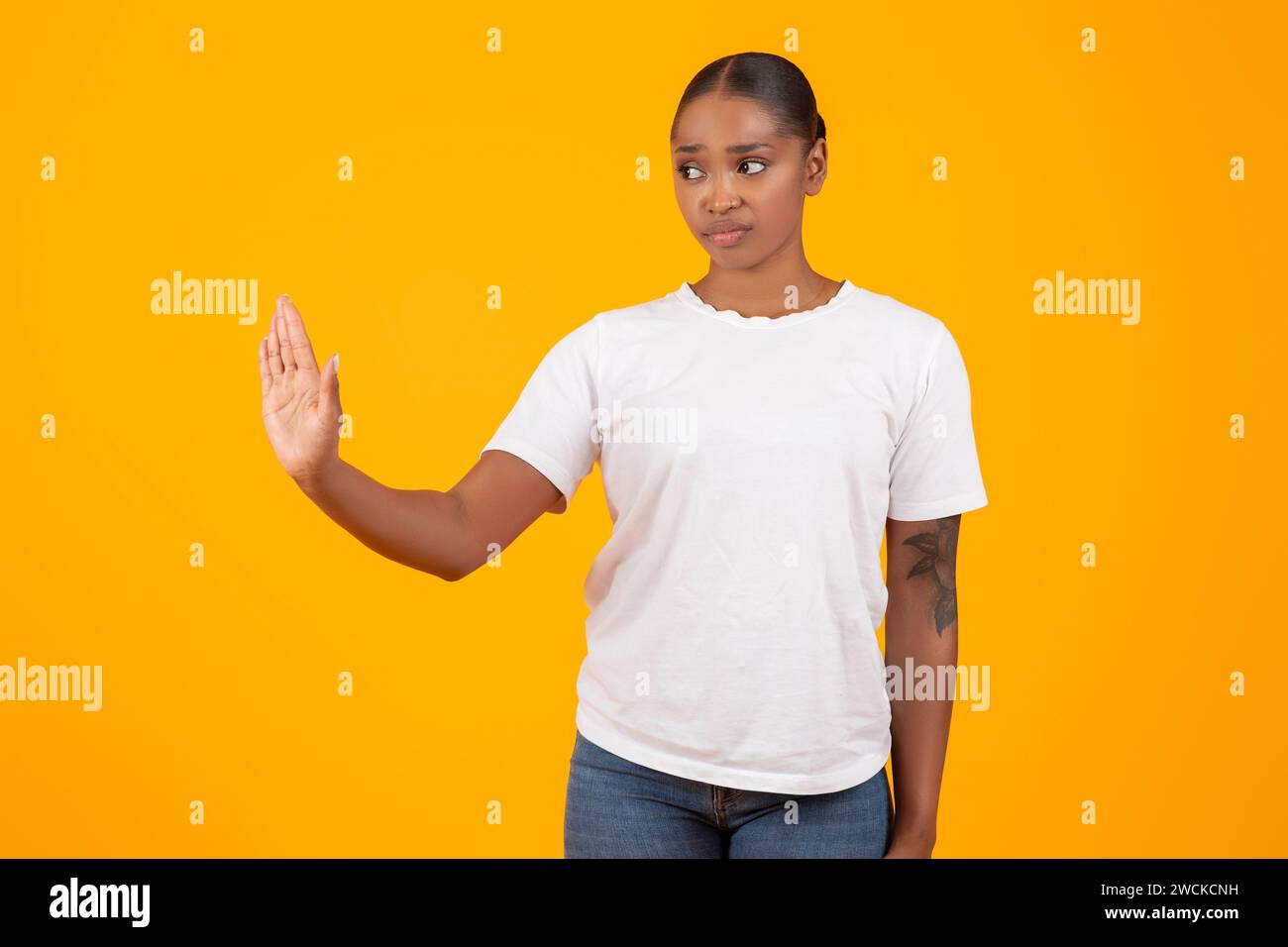 black woman makes stop gesture with hand on yellow background Stock Photo