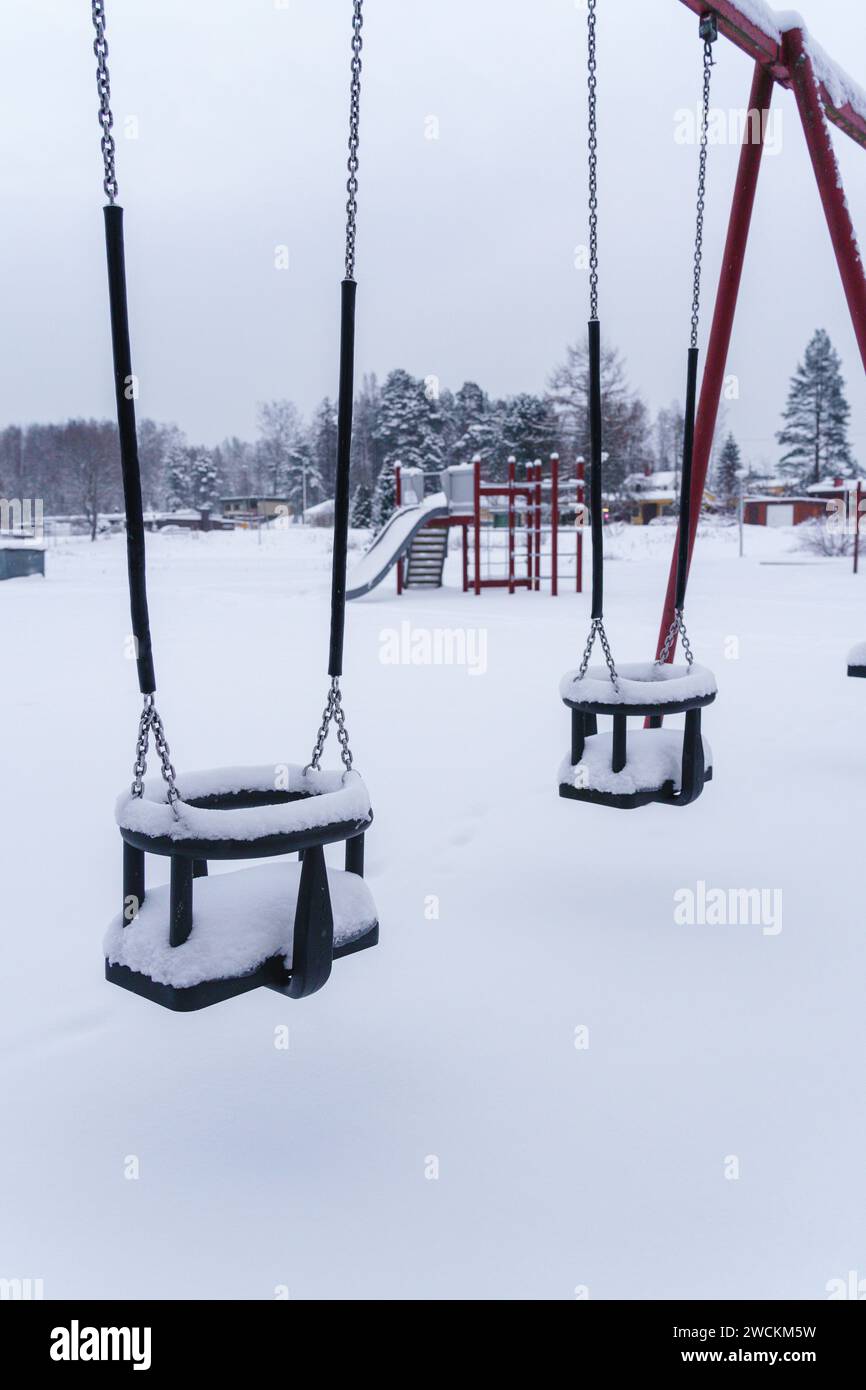 Swings covered in snow at the empty playground in winter. Finland. Stock Photo