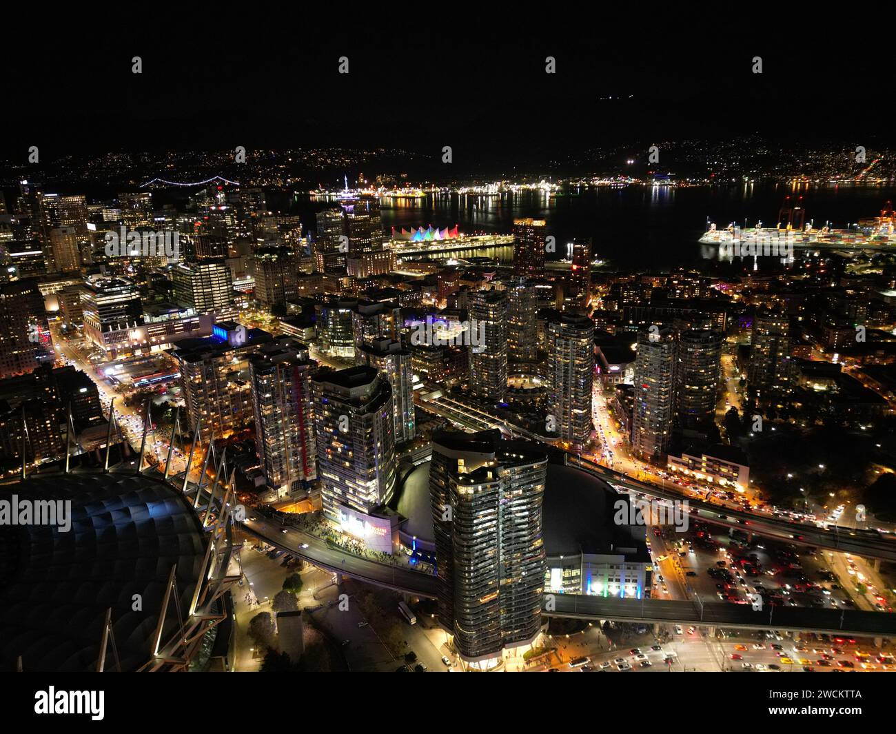 Cityscape at night with bustling streets filled with cars and pedestrians Stock Photo