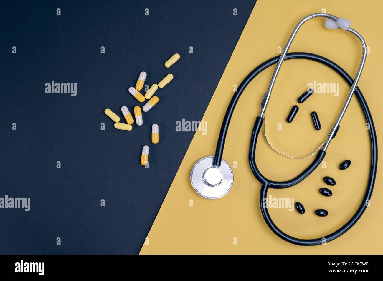 Stethoscope and capsules on yellow and black background. Healthcare, medical exam, insurance,  concept. Stock Photo