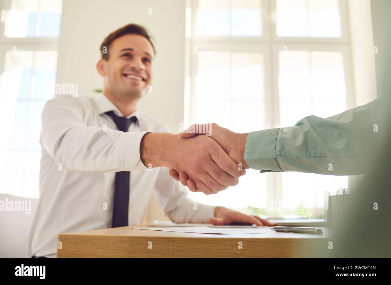 Two business people in office making deal. Two men shaking hands celebrating business achievement. Stock Photo