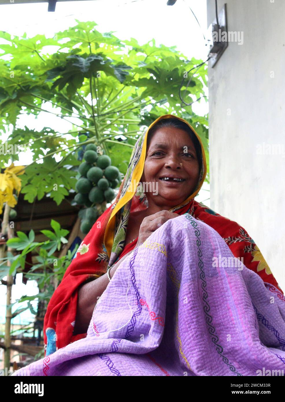 Rural Bangladeshi women sewing and embroidering bed sheets, pillow cases, rugs, table cloths and other household items which is their livelihood. Gucchogram, Jhinaigati, Sherpur. Bangladesh. Stock Photo