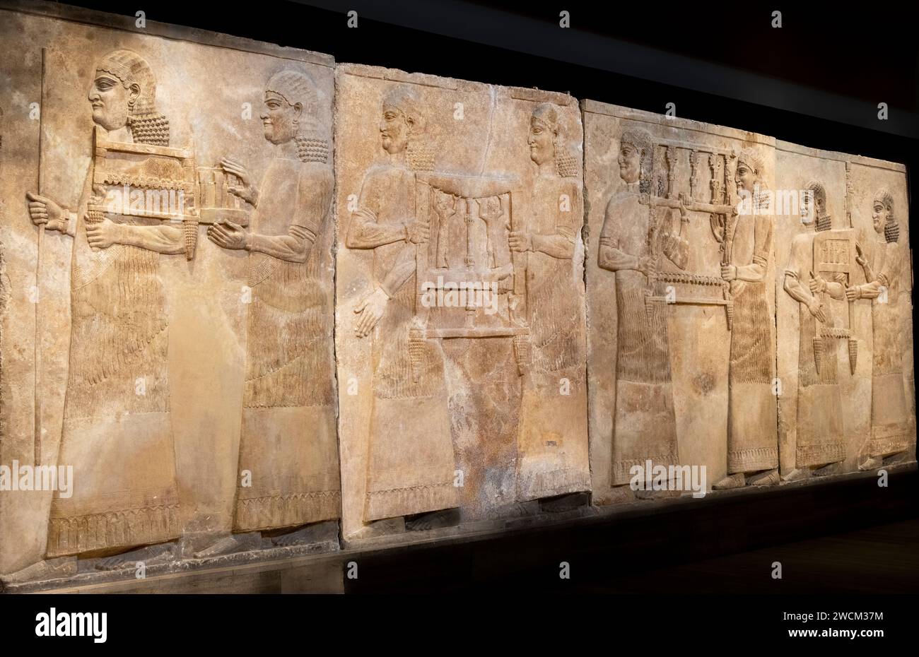 carved stone relief of servants carrying chairs,  Assyrian palace of Dur-Sharrukin, Khorsabad, Iraq, now in the Iraq Museum, Baghdad, Iraq Stock Photo