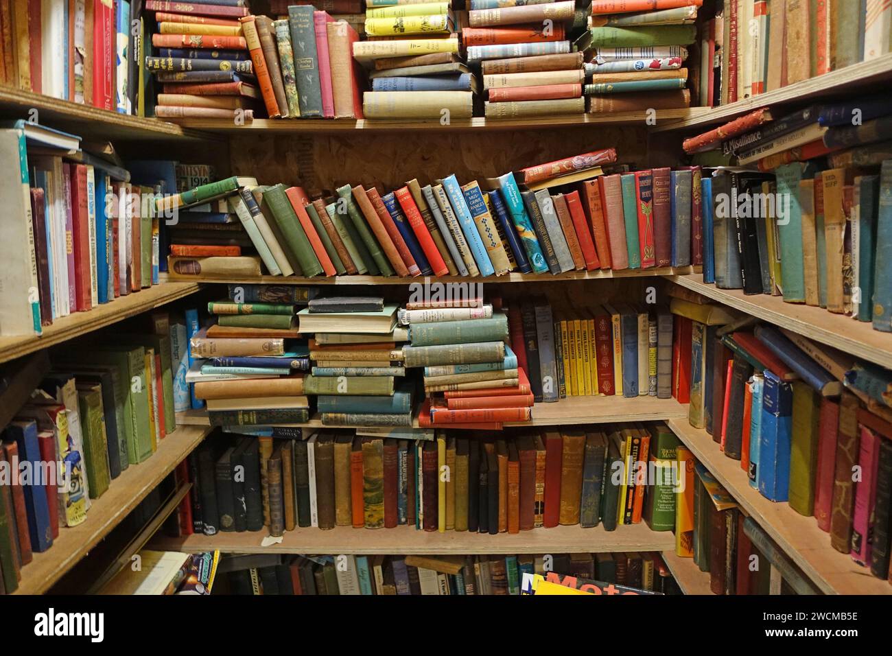 Books stacked in a disorganised way in an old bookshop on Morecambe Stock Photo