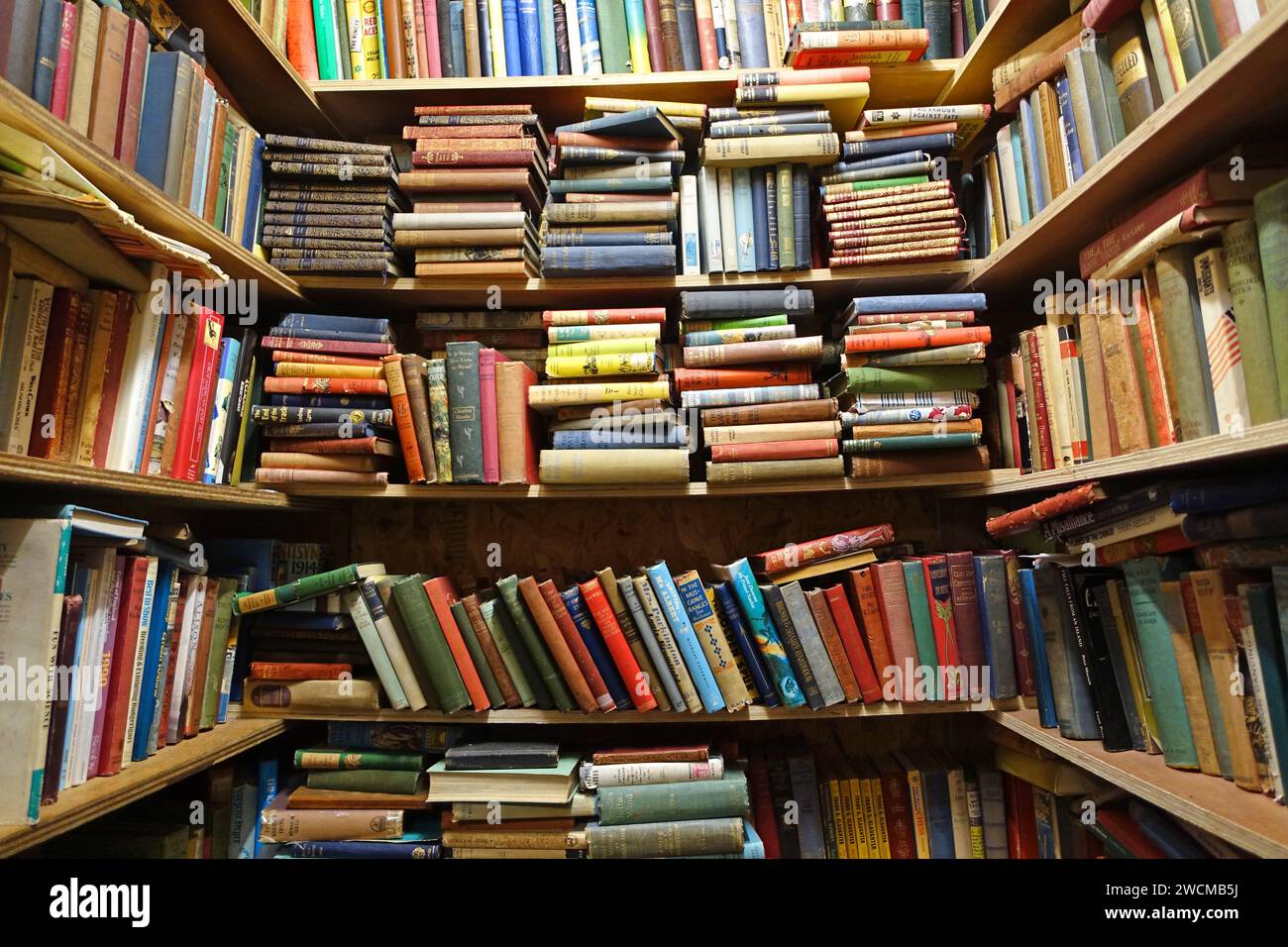 Books stacked in a disorganised way in an old bookshop on Morecambe Stock Photo